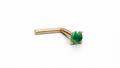 A gold-colored nose stud with a green gemstone is shown against a plain white background.