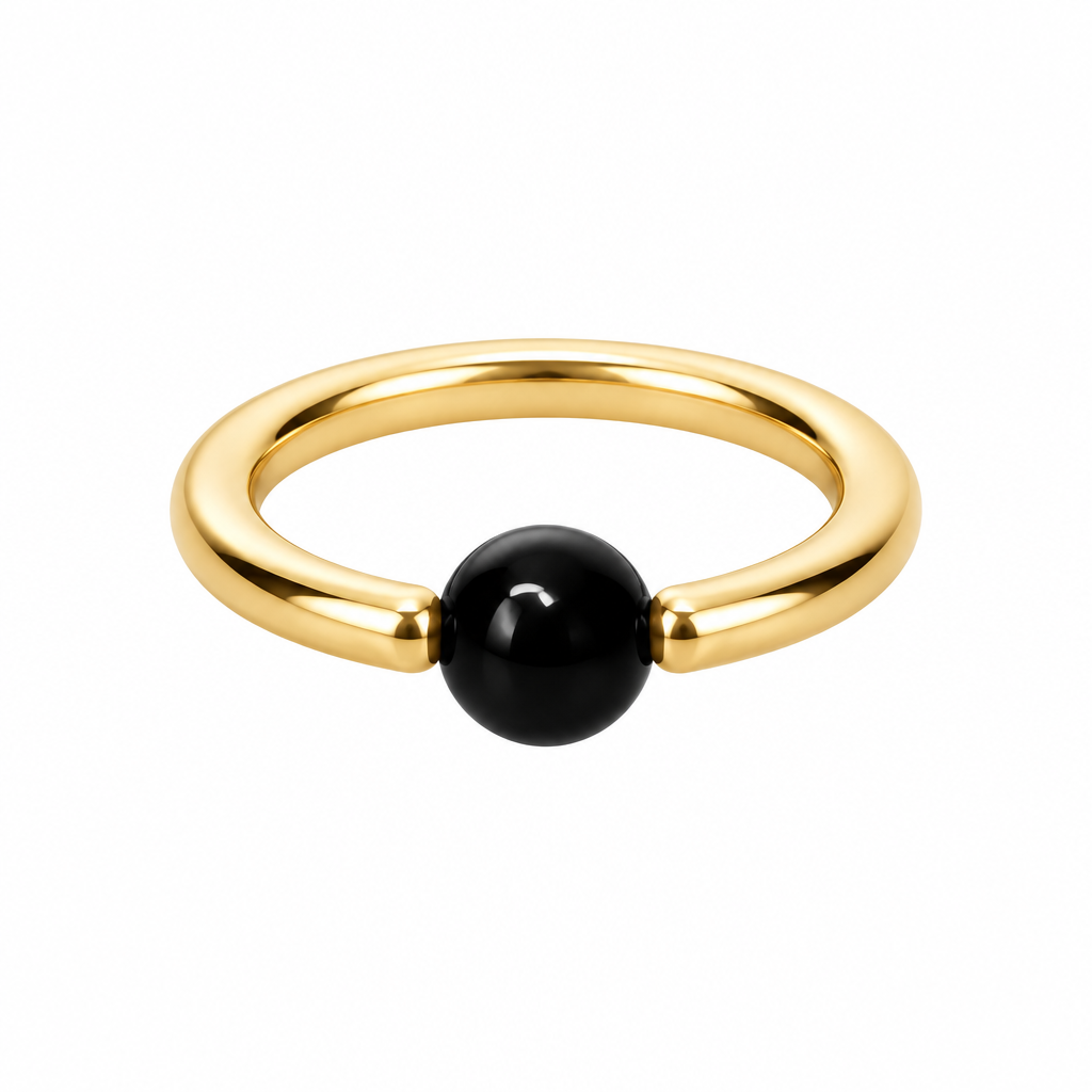 A minimalist gold ring with a smooth, polished black spherical bead set into the front, photographed on a clean white background.