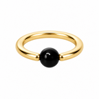A minimalist gold ring with a smooth, polished black spherical bead set into the front, photographed on a clean white background.